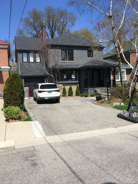 Dark two-storey house with driveway, new eavestrough, fascia and window capping
