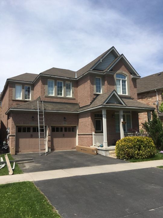 Brick house front with ladder, new eavestrough being installed