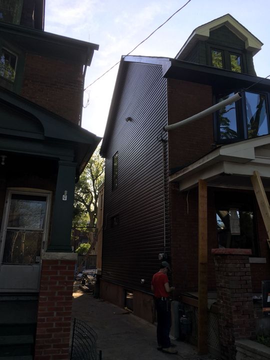 Tall narrow house with new dark siding on the side wall