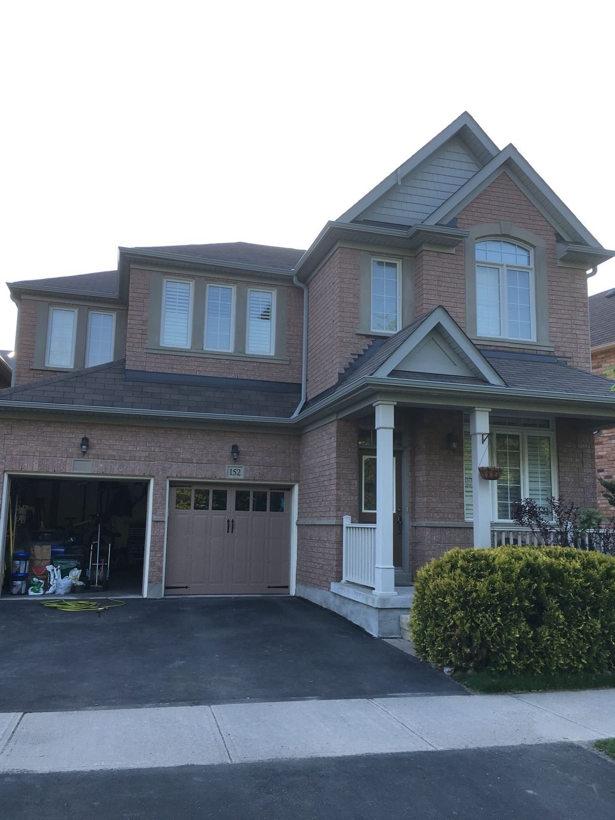 Two-storey brick house in Toronto with a new white eavestrough and downspout along the garage and porch roofline